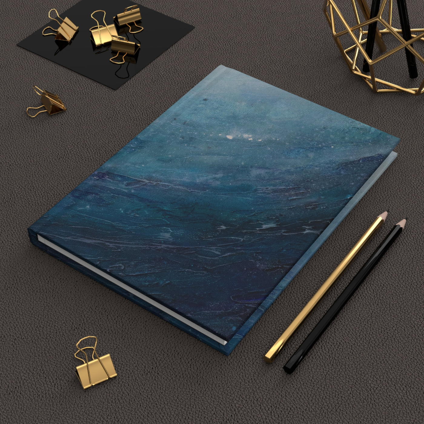 Blue notebook with gold and black office supplies on a dark surface
