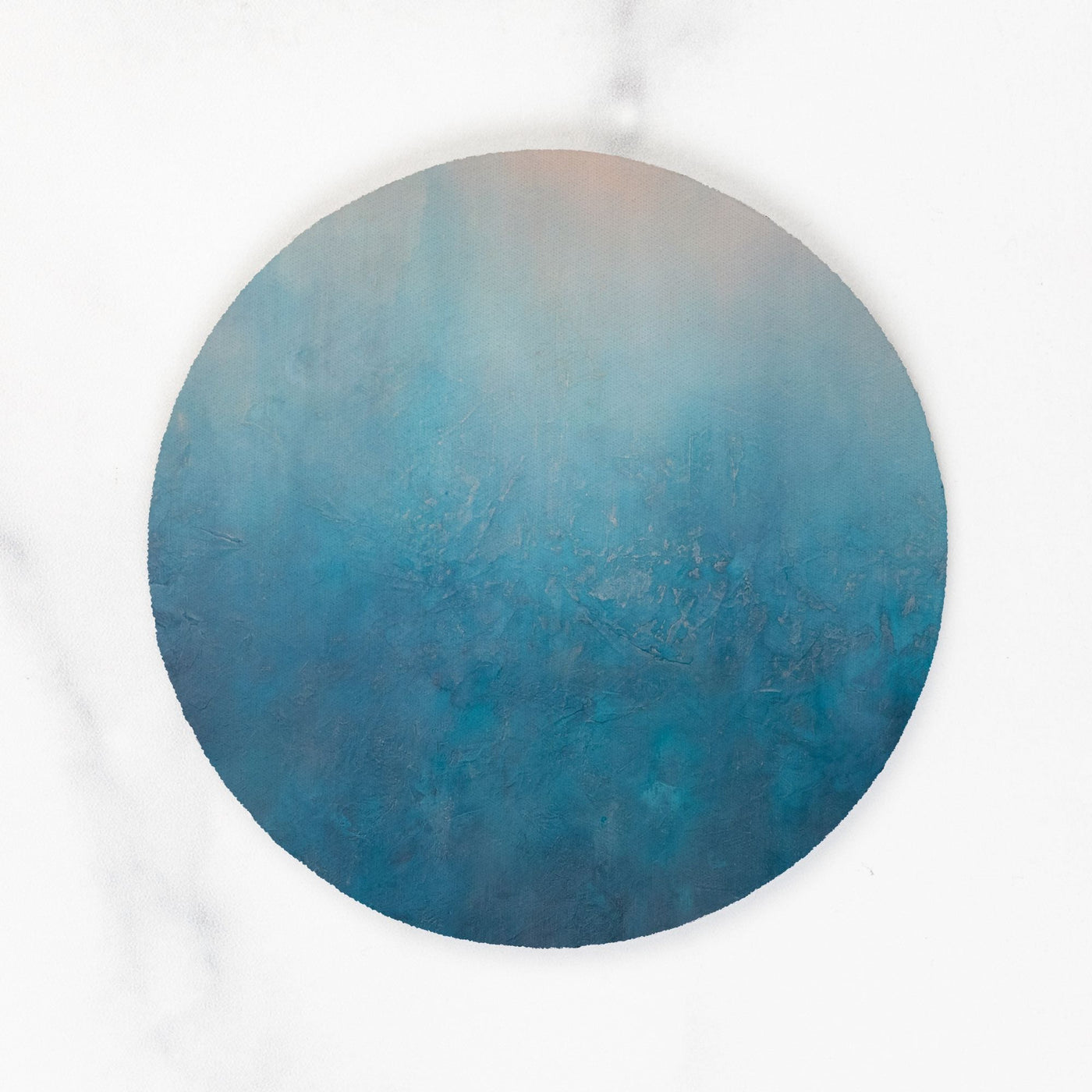 Round blue coaster on a white marble background